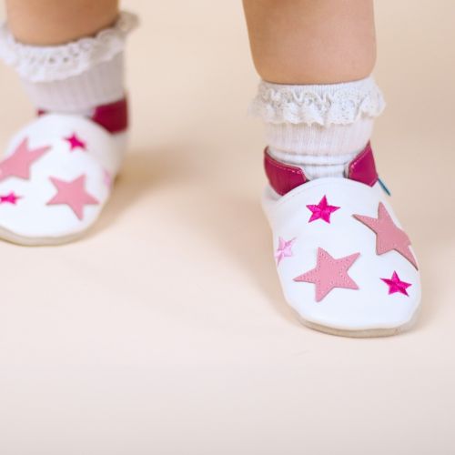 Toddler wearing white leather shoes with pink stars.