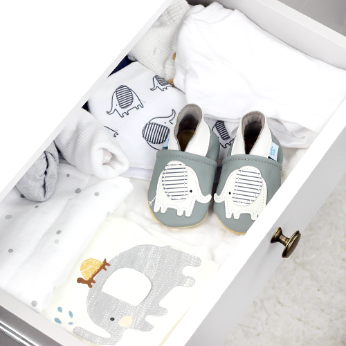 Grey leather shoes with elephant, in drawer with baby blankets.