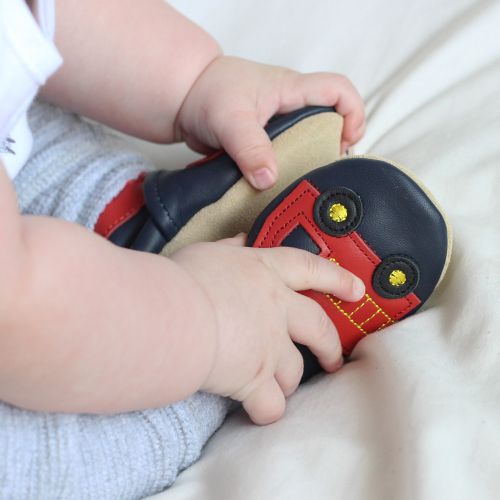 Toddler wearing navy blue Dotty Fish shoes with red ankle trim and red fire engine design.