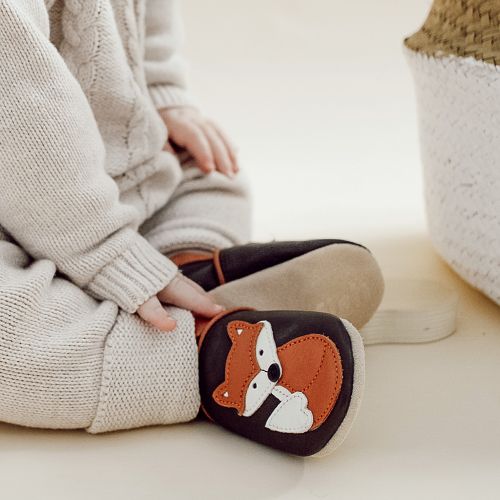 Toddler wearing brown leather Dotty Fish first walker shoes with orange and white fox design.