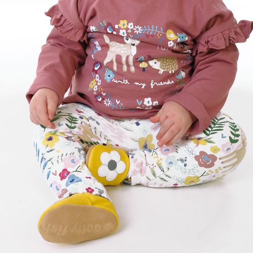 Toddler girl wearing yellow Dotty Fish barefoot shoes with grey ankle trim and white flower design.