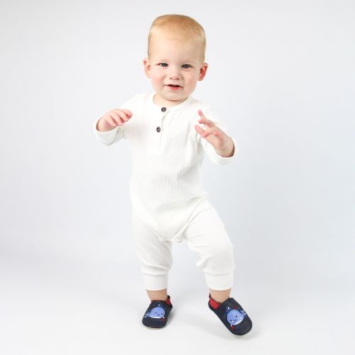 Toddler taking first steps, wearing navy leather Dotty Fish first walker shoes with blue whale design.