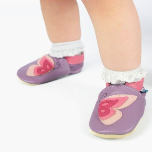 Toddler wearing purple leather shoes with pink butterfly.