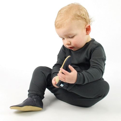 Toddler boy sitting on floor wearing navy blue leather Dotty Fish first walker shoes.