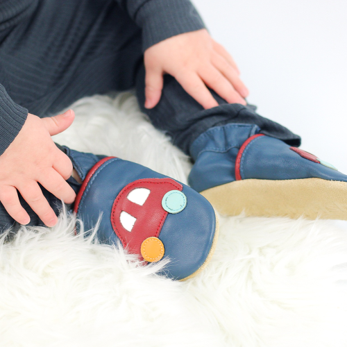 Toddler wearing navy blue Dotty Fish shoes with red car design.