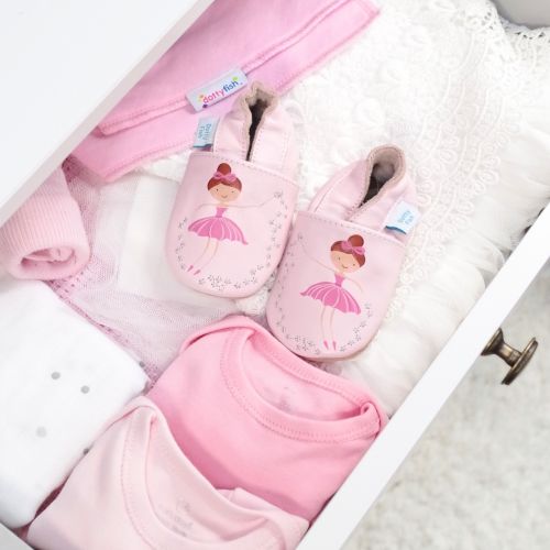 Pink leather ballerina shoes in drawer with baby clothing.