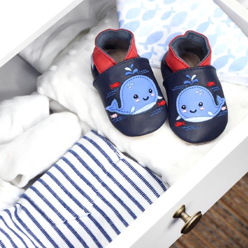 Navy leather baby shoes with blue whale design, in drawer with baby blankets.