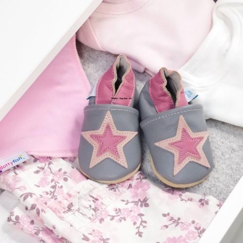 Grey and pink leather shoes in drawer with baby clothing.