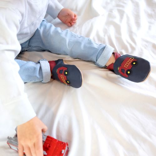 Toddler wearing navy blue Dotty Fish shoes with red ankle trim and red fire engine design.