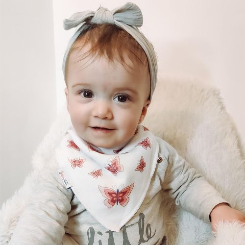 Baby girl wearing Dotty Fish white cotton bandana bib with pink butterfly pattern.