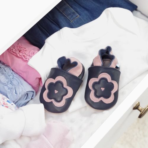 Leather navy and pink flower shoes in drawer with baby clothing.