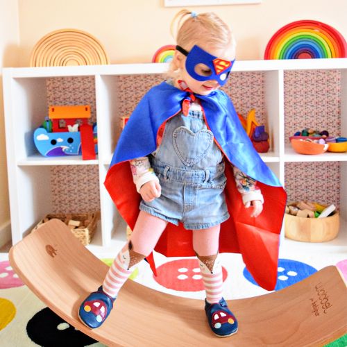 Toddler wearing Dotty Fish car shoes, playing and dressed in cape.