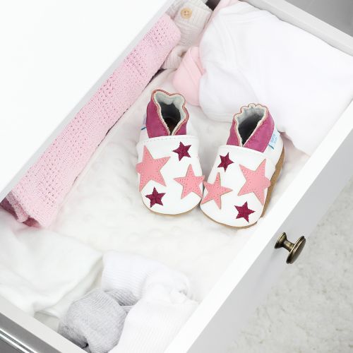 White leather shoes with pink stars, in drawer with baby clothing.