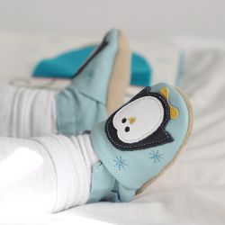 Baby wearing blue leather shoes with penguin design.