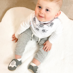 Baby wearing Dotty Fish cotton bandana bib with grey elephant pattern.