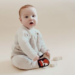 Baby boy sitting, wearing brown Dotty Fish shoes with orange and white fox design.