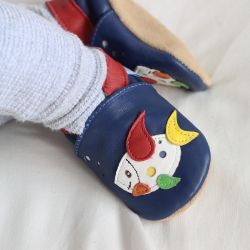 Baby wearing blue Dotty Fish soft sole pre-walker shoes with multicoloured fish design.