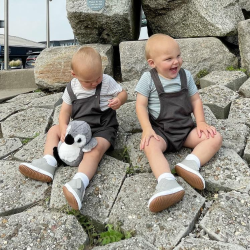 Twin boys sitting on rocks wearing Dotty Fish light grey leather pre-walker rubber sole slip-on shoes.
