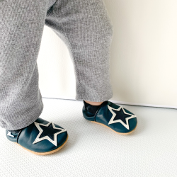 Toddler boy standing wearing navy blue leather Dotty Fish shoes with white and navy star design.