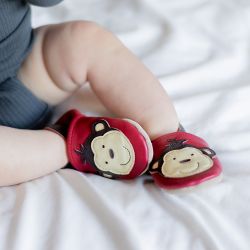 Toddler wearing red Dotty Fish shoes with brown and cream monkey design.