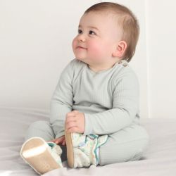 Baby boy wearing safari cotton booties, sitting on bed.