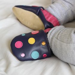 Toddler wearing navy leather Dotty Fish first walker barefoot shoes with pink ankle trim and multicoloured spots.