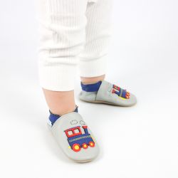 Toddler wearing pale grey Dotty Fish shoes with blue ankle trim and blue and red train design.