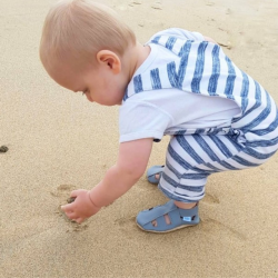 Small boy playing on beach wearing grey leather Dotty Fish first walker barefoot sandals.
