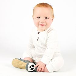 Smiling baby boy sitting on floor, wearing grey Dotty Fish shoes with white and black panda design.