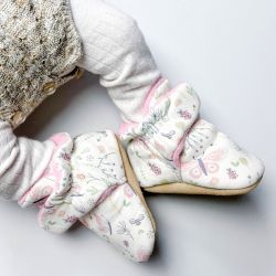 Baby girl wearing cream cotton Dotty Fish booties with pink fleece lining and butterfly and bee pattern.