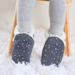 Child sitting wearing Dotty Fish dark grey slippers with silver stars.