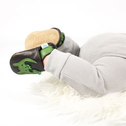 Baby wearing brown Dotty Fish shoes with green dinosaur design.