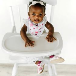 Baby girl wearing Dotty Fish white cotton bandana bib with pink stars pattern.