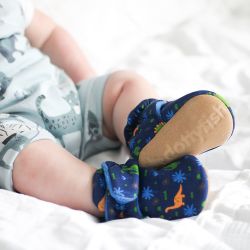 Baby boy wearing dark blue cotton Dotty Fish booties with blue fleece lining and colourful dinosaur pattern.