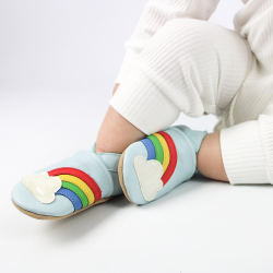 Toddler wearing light blue leather Dotty Fish first walker shoes with rainbow and cloud design.