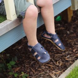 Toddler wearing navy leather Dotty Fish first walker barefoot sandals.