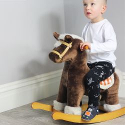 Toddler wearing navy Dotty Fish infant shoes with silver and orange robot design sitting on rocking horse.