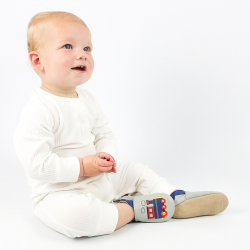 Small boy sitting on floor wearing pale grey Dotty Fish train shoes.