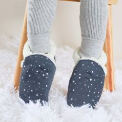 Child sitting wearing Dotty Fish dark grey slippers with silver stars.