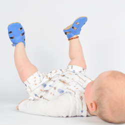 Baby boy lying down, wearing blue leather Dotty Fish first walker barefoot sandals.