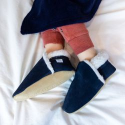 Close up of navy suede Dotty Fish barefoot slippers, with fleece lining, worn by small child.