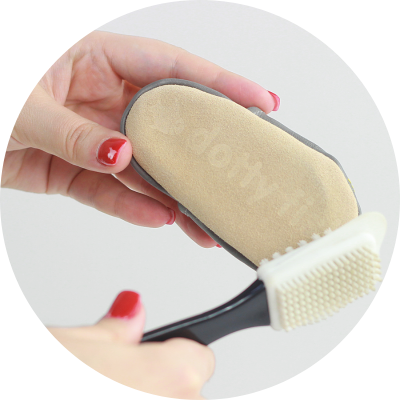 Someone cleaning soft suede soles with a suede brush